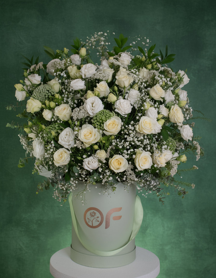 One-metre tall luxury white rose and lisianthus flower arrangement in a branded round box with greenery and baby's breath.