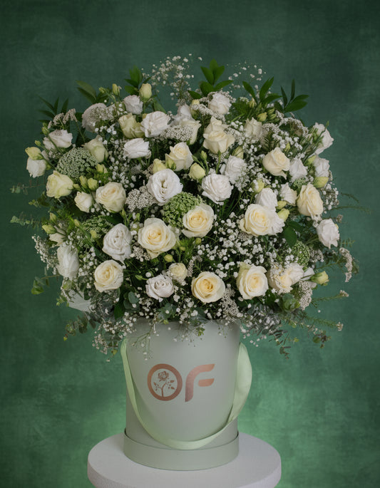 One-metre tall luxury white rose and lisianthus flower arrangement in a branded round box with greenery and baby's breath.