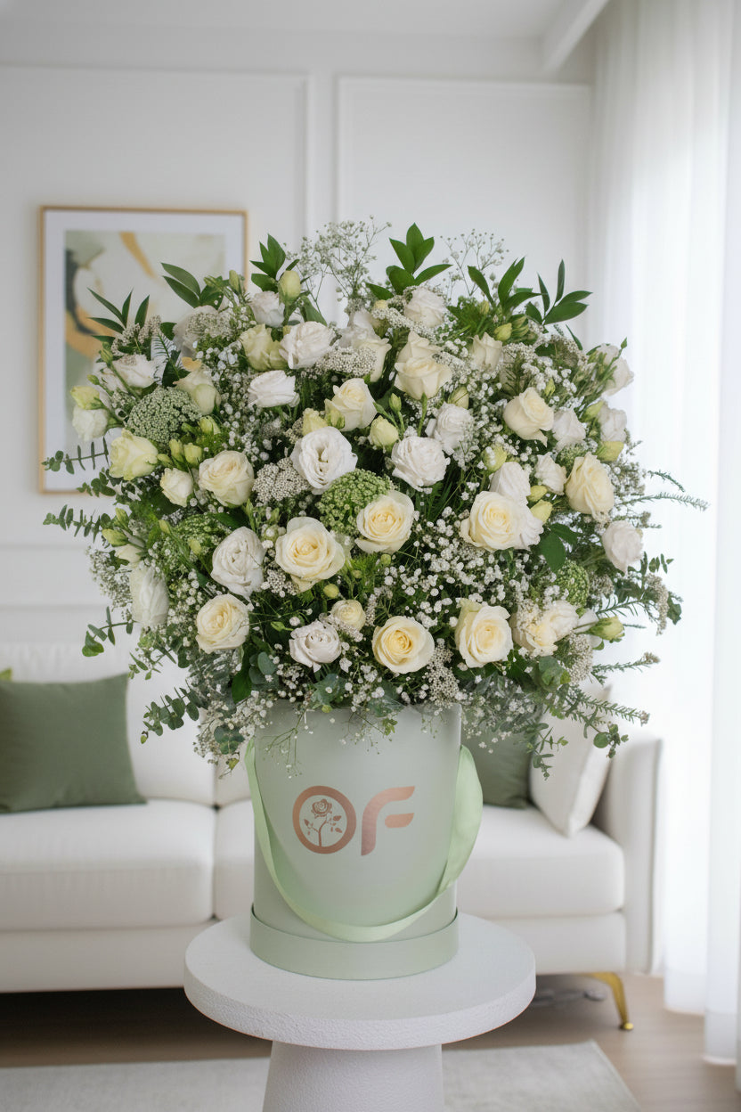 One-metre tall luxury white rose and lisianthus flower arrangement in a branded round box with greenery and baby's breath.