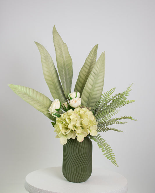 Green blooms arranged in a modern, matte olive vase with gentle wave textures 