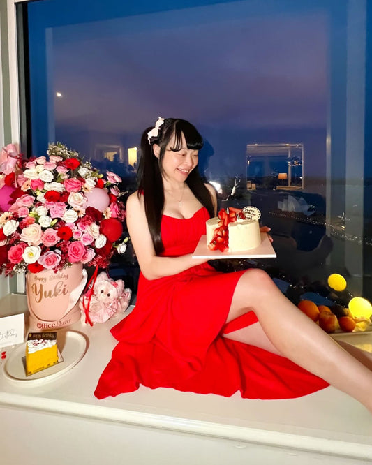 Celebration flower box arrangement with pink and red flowers, balloons, and cascading red ribbon details