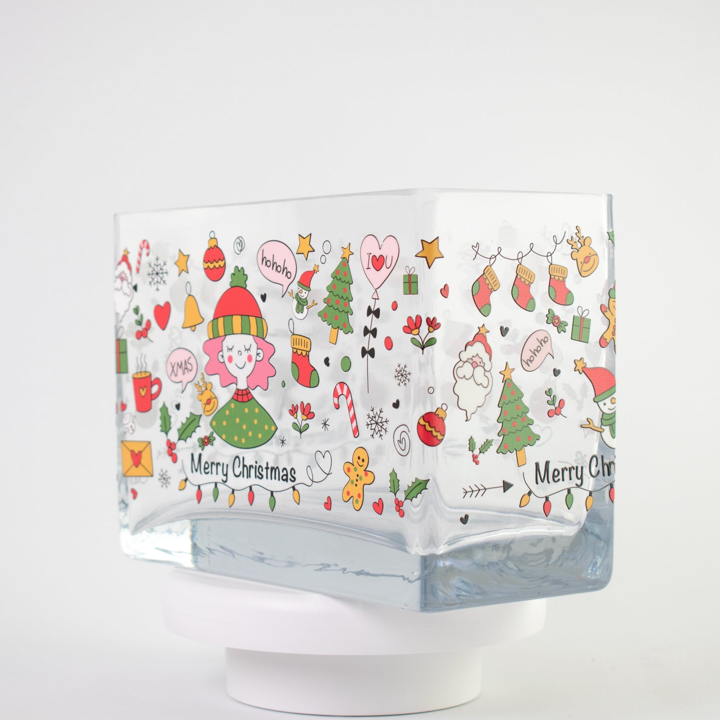 Clear glass vase with a colourful Christmas design featuring Santa, candy canes, gifts, stars, and “Merry Christmas” text — size 20x10x15 cmH.