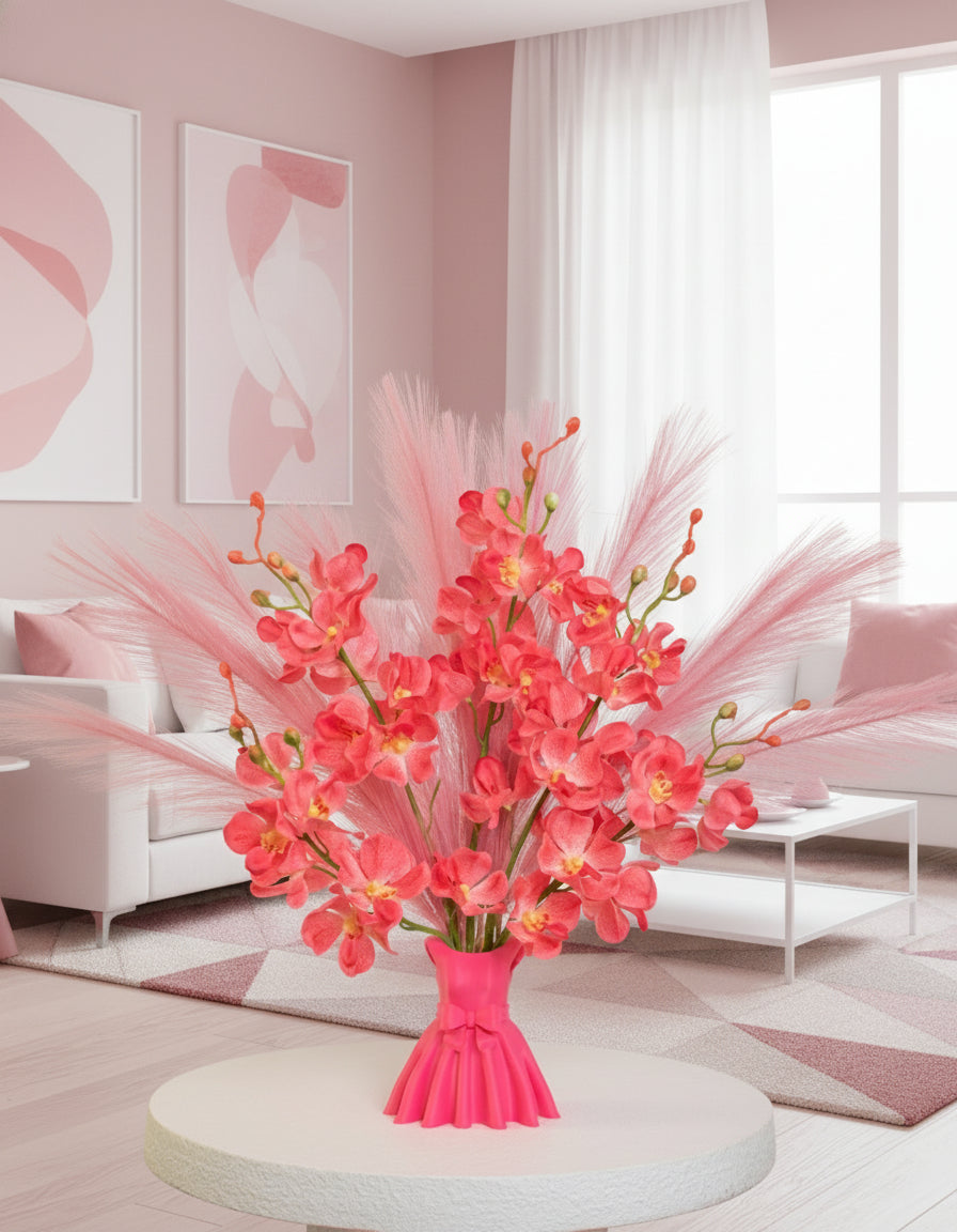 Artificial flower arrangement featuring bright pink orchids and soft pink pampas grass, beautifully styled in a sculptural pink vase shaped like an elegant dress, placed on a round white table against pink room background.