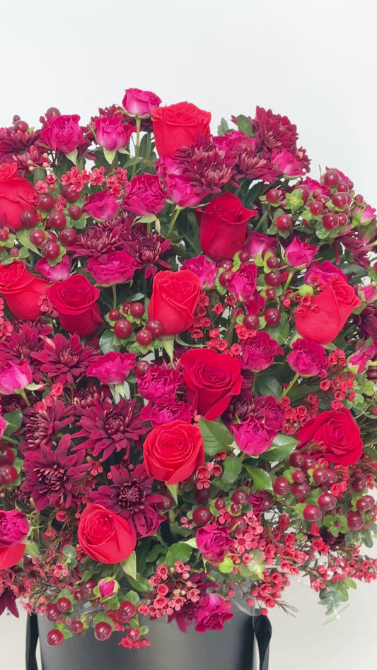 Luxury flower gift box with red roses,  blooms, and textured berry details for celebrations