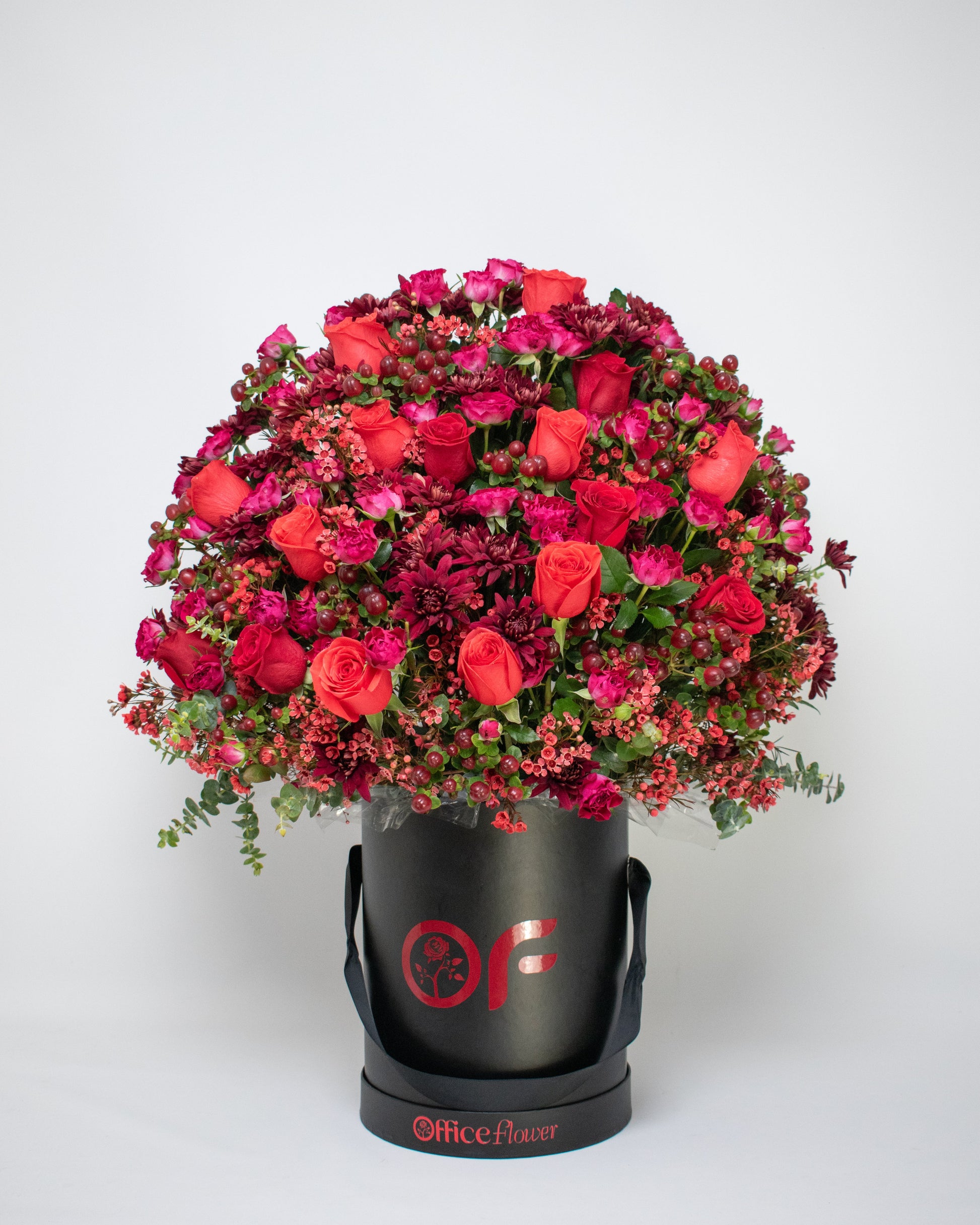 Red rose arrangement in a black gift box with red fillers and black ribbon handles
