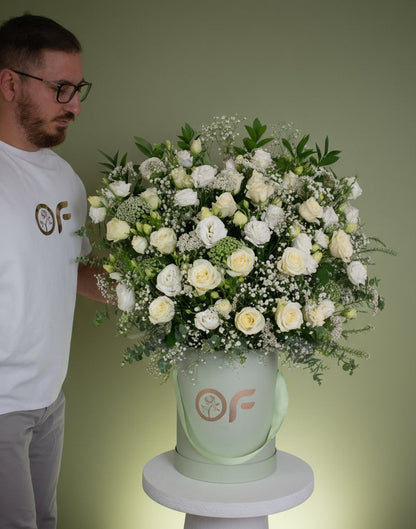 One-metre tall luxury white rose and lisianthus flower arrangement in a branded round box with greenery and baby's breath.